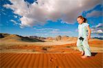 Namib Rand Nature Reserve, Namibia. Ein kleiner Junge führt quer durch die wellige Oberfläche des eine Sanddüne in der Wüste Namib.