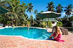 Seychelles, Mahe. A girl dabbling her toes in the pool at L Habitation Cerf, a hotel on an island off the north coast