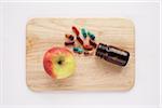 Apple and Bottle of Pills on Cutting Board