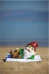 Garden Gnome Lying on Towel on Beach