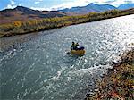 Woman packrafts down the Sanctuary River in Denali National Park, Interior Alaska, Autumn