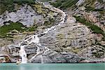 A tour boat passes a waterfall near the base of Endicott Arm Fjord and Dawes Glacier in Tracy Arm-Fords Terror Wilderness, Tongass National Forest, Inside Passage of Southeast Alaska, Summer