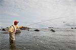 Mouche de pêcheur à la ligne de pêche dans la baie de Bristol près de Crystal Creek Lodge avec un hydravion vole en arrière-plan, King Salmon, sud-ouest de l'Alaska, l'été