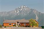 Evening view of the Mat-Su Visitors Bureau cabin with Pioneer Peak in the background, Mat-Su Valley, Southcentral Alaska, Summer. Digitally Altered.