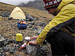 Backpacker prepares food at camp below Mt. Chamberlin, Brooks Range, ANWR, Arctic Alaska, Summer
