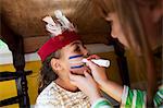 Girl putting Native American face paint on another girl