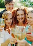 A group of smiling people raising their glasses and looking into the camera.