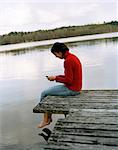 Une femme avec un téléphone portable assis sur un pont.