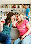 Two women laughing in a sofa.