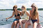 Three women sitting in a boat, laughing.