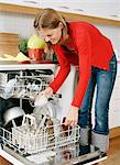 A woman putting dishes in a dishwasher.