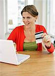 A woman with credit cards by a computer.