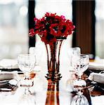 Red anemones in a vase on a set table.