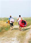 Two men walking on the beach carrying a rubber dinghy.