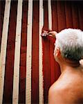 A man painting a house red.