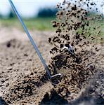 A golf club swinging in a sand trap, close-up.
