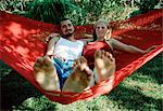 A young couple sitting in a red  hammock.