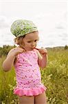 A girl eating a straw of wild strawberries.