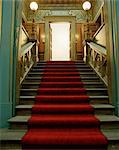 Un tapis rouge conduit vers le haut de l'escalier.