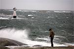 Un homme debout près d'une mer orageuse.