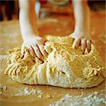 A child kneading a dough.