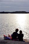 Silhouette d'un couple assis au bord de la mer au coucher du soleil.