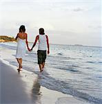 Young couple walking at the water's edge, Thailand.