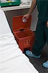 Healthcare professional putting trash in biohazard waste receptacle