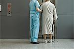 Nurse helping patient wait for elevator in hospital corridor