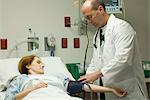 Doctor putting blood pressure cuff on patient in hospital