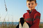 Boy outdoors holding stuffed toy penguin