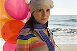 Preteen girl with bunch of balloons at beach