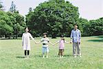 Familie steht In einem Park, Hand in Hand