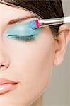 Young woman applying turquoise eyeshadow