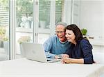 Mature couple using laptop with credit card