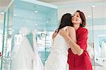 Daughter trying on wedding dress, embracing mother
