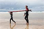 Père et fils transportant de planche de surf