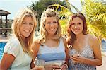 Portrait of three smiling women by pool