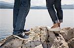 Homme et femme debout sur le rocher au bord de mer