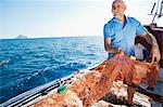 Fisherman on boat pulling in nets