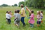 Kids dancing round maypole in meadow