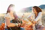 Women playing the guitar in the grass