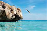 Homme plongeant de rochers dans la mer