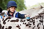 Young girl grooming her pony