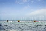 3 kayakers in front of mills