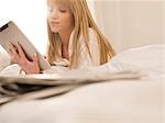 Junge Frau mit Tablet PC im Bett