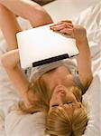 Junge Frau mit Tablet PC im Bett