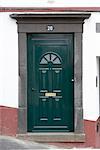 Madeira. Dark green painted front door on sloping street with Number 20