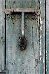 Madeira. Detail of dilapidated and rusty metal door knocker on decaying front door with peeling paint