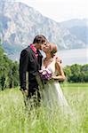 Newlywed Couple s'embrassant dans champ près du lac et des montagnes